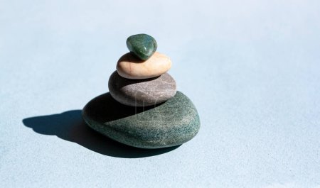 Téléchargez les photos : "Montagne de pierre sur fond bleu, une tour de quatre pierres, simples pierres équilibrées, simplicité, harmonie et équilibre. Concept minimaliste." - en image libre de droit
