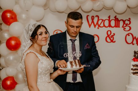 Téléchargez les photos : "marié et mariée au mariage couper leur grand gâteau blanc multi-niveaux goût qu'il nourri les uns des autres." - en image libre de droit