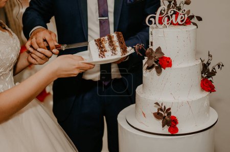 Téléchargez les photos : "marié et mariée au mariage couper leur grand gâteau blanc multi-niveaux goût qu'il nourri les uns des autres." - en image libre de droit