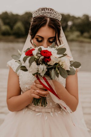 Téléchargez les photos : "Européen caucasien jeune femme aux cheveux noirs mariée fille tenant son bouquet fleurs dans les mains." - en image libre de droit