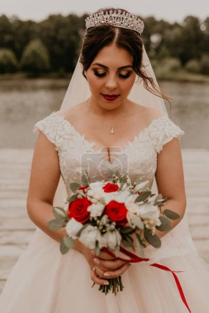 Photo for "European Caucasian young black-haired woman bride girl holding her bouquet flowers in hands." - Royalty Free Image