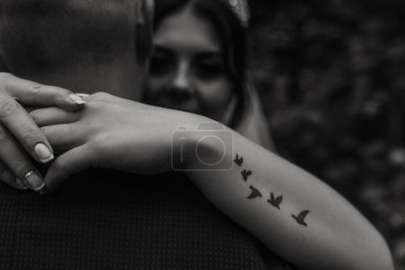 Téléchargez les photos : "mariée câlins marié bras tatouage sous la forme d'oiseaux volants avale" - en image libre de droit