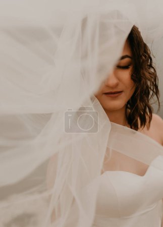 Téléchargez les photos : "mariée femme avec coupe de cheveux courte en corset de mariage blanc robe bustier et avec un long voile en mousseline de soie sur la tête" - en image libre de droit