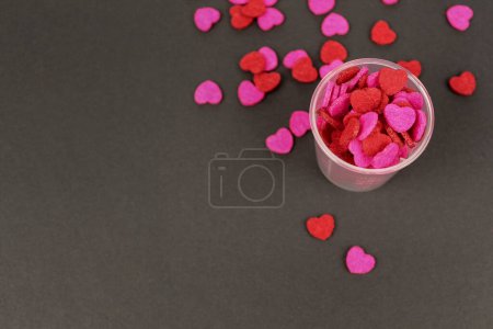 Téléchargez les photos : "Bonbons coeur rose rouge en tasse transparente fond foncé Love Valentine Concept" - en image libre de droit