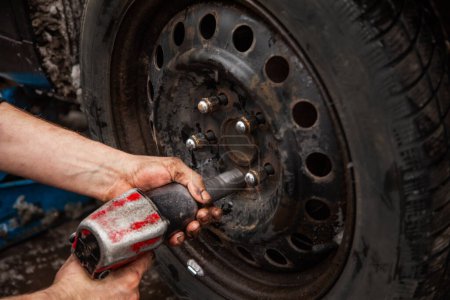 Photo for "car mechanic unscrews car wheel, wheel mount" - Royalty Free Image