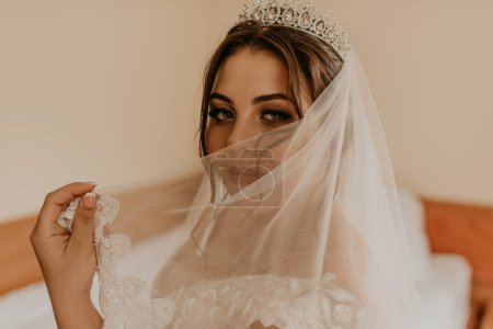 Photo for "woman bride in white wedding dress with long veil and tiara on head" - Royalty Free Image