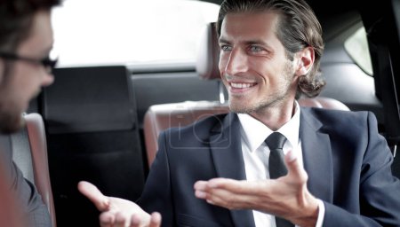 Téléchargez les photos : Partenaires d'affaires assis sur le siège arrière de la voiture - en image libre de droit