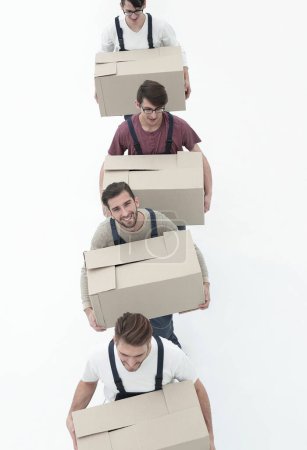 Téléchargez les photos : Jeunes déménageurs tenant des boîtes debout dans une rangée, isolés sur blanc - en image libre de droit