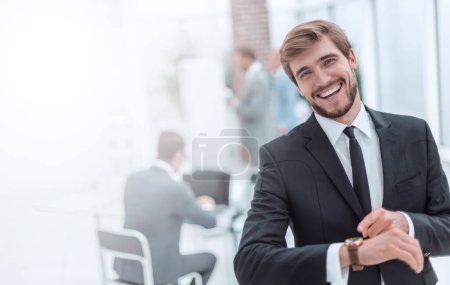 Téléchargez les photos : Homme d'affaires souriant pointant vers sa montre-bracelet. - en image libre de droit