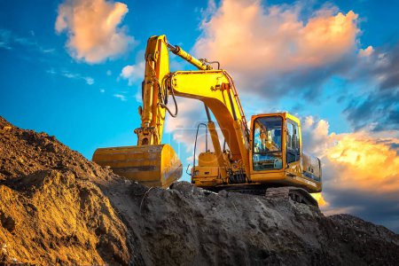 Photo for A stopping yellow excavator at an incredibly beautiful sunset - Royalty Free Image