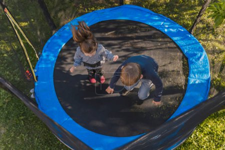 Téléchargez les photos : Enfants heureux sauter sur le trampoline - en image libre de droit