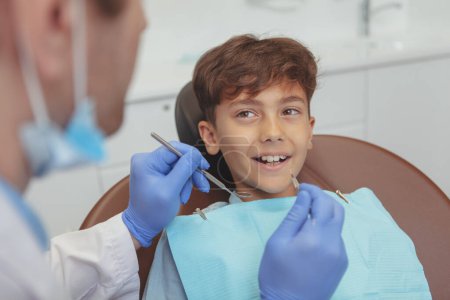 Téléchargez les photos : "Charmant jeune garçon se faire examiner les dents chez le dentiste" - en image libre de droit