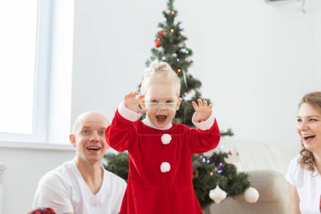 Foto de Niño pequeño con implante coclear grita felizmente el fondo del árbol de Navidad: sordera e innovadoras tecnologías médicas para audífonos - Imagen libre de derechos