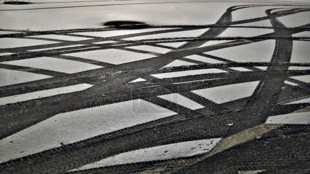 Foto de Cruzando huellas de neumáticos en nieve nueva sobre asfalto. - Imagen libre de derechos