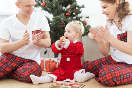 Foto de Toddler child with cochlear implant plays with parents under Christmas tree - deafness and innovating medical technologies for hearing aid - Imagen libre de derechos