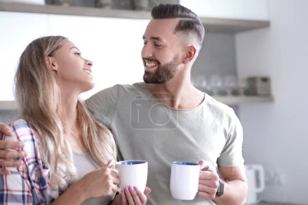 Foto de "joven pareja bebiendo café de pie en la cocina" - Imagen libre de derechos
