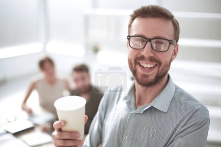 Téléchargez les photos : Vue arrière. homme d'affaires avec une tasse de café regardant la caméra - en image libre de droit