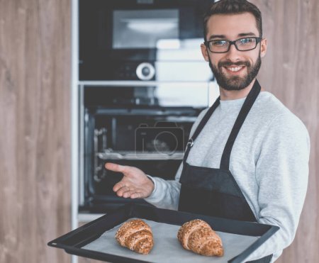 Téléchargez les photos : "homme souriant tenant un plateau de croissants frais" - en image libre de droit