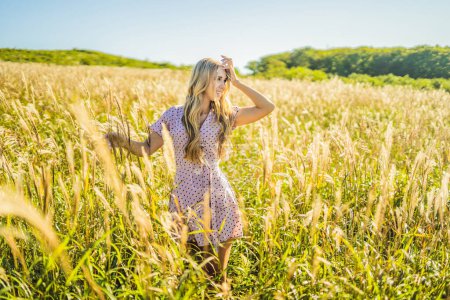 Photo for "Young beautiful woman in autumn landscape with dry flowers, wheat spikes. Fashion autumn, winter. Sunny autumn, fashion photo" - Royalty Free Image
