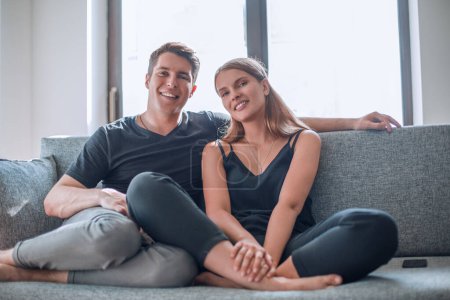Photo for Happy young couple sitting on the couch in their new apartment . - Royalty Free Image