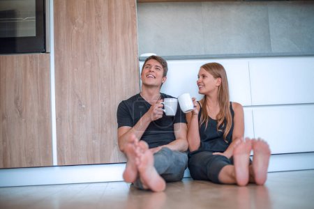 Photo for "young couple sitting on the floor in new kitchen." - Royalty Free Image