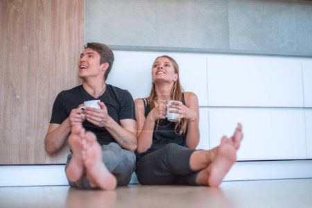 Téléchargez les photos : Jeune couple assis sur le sol dans la nouvelle cuisine. - en image libre de droit