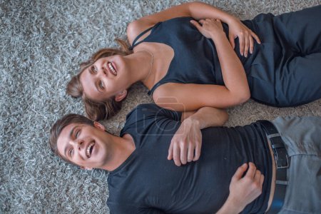 Photo for Happy young couple relaxing lying on the carpet - Royalty Free Image