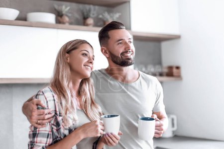 Photo for "young couple drinking coffee standing in the kitchen" - Royalty Free Image