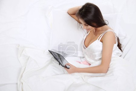 Téléchargez les photos : "Femme couchée au lit avec sa tablette PC et surfer sur internet
" - en image libre de droit