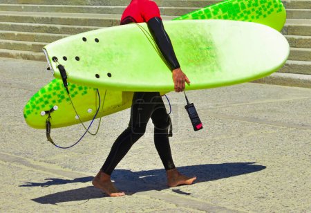Photo for "Surfer in wet suit after training and in hands holds surfboards" - Royalty Free Image