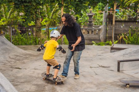 Photo for "Athletic boy learns to skateboard with a trainer in a skate park. Children education, sports" - Royalty Free Image