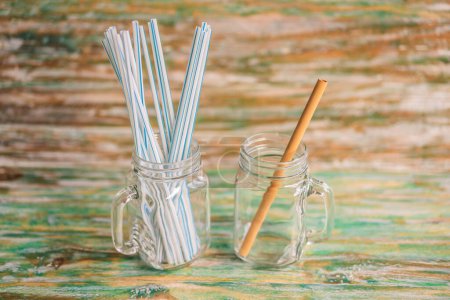 Photo for "Bamboo drinking straw vs disposable straws on wooden painted background. Zero waste concept" - Royalty Free Image