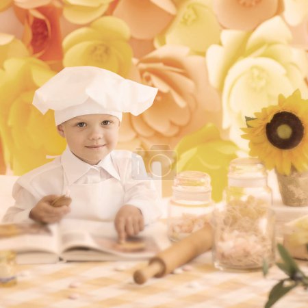 Photo for "happy little boy with a book chef preparing Breakfast in the kit" - Royalty Free Image