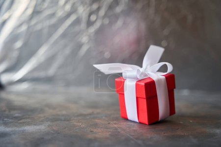 Téléchargez les photos : Petite boîte cadeau rouge avec arc blanc sur fond sombre - en image libre de droit