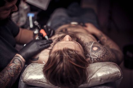 Photo for Professional tattooer demonstrates process of making a tattoo tattoo studio - Royalty Free Image