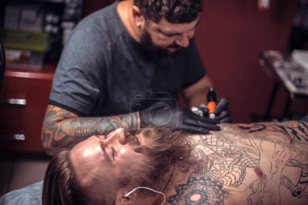 Téléchargez les photos : Tatoueur montrant le processus de fabrication d'un tatouage dans le salon - en image libre de droit