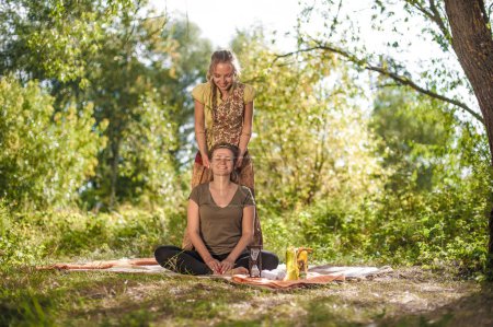 Téléchargez les photos : Guérisseuse applique ses compétences de massage sur son client sur l'herbe de la forêt. - en image libre de droit
