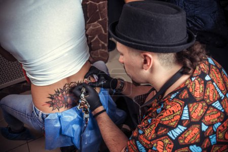 Téléchargez les photos : Maître tatoueur travail tatouage dans le salon de tatouage - en image libre de droit