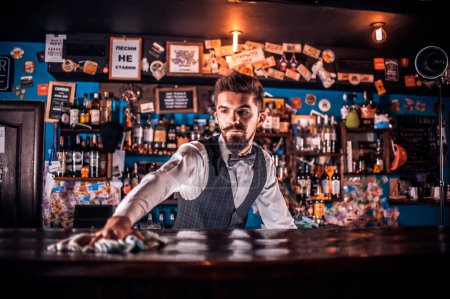 Foto de Retrato de barman añade ingredientes a un cóctel mientras está de pie cerca del mostrador del bar en el bar - Imagen libre de derechos