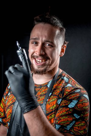 Téléchargez les photos : Maître de tatouage et un pistolet de tatouage en studio de tatouage - en image libre de droit
