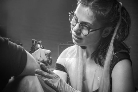 Téléchargez les photos : Tatoueur professionnel fait des photos de tatouage dans le salon - en image libre de droit