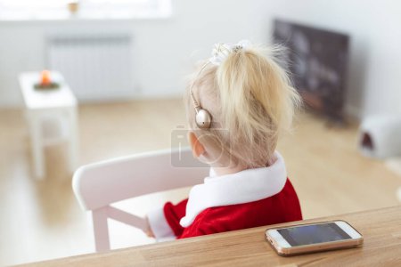 Téléchargez les photos : Deaf child girl with cochlear implant on living room - deafness diversity and innovative hearing aid medical technologies - en image libre de droit