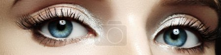 Foto de Primeros ojos femeninos con maquillaje brillante, cejas grandes formas, pestañas largas extremas. Celebra el maquillaje, sombras de ojos de lujo - Imagen libre de derechos