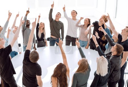 Téléchargez les photos : Groupe de jeunes gens divers applaudissent debout autour d'une table ronde - en image libre de droit