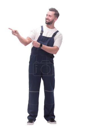 Photo for Smiling man in overalls pointing to a copy of the space - Royalty Free Image