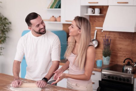 Photo for Happy married couple rolling out dough in the kitchen - Royalty Free Image