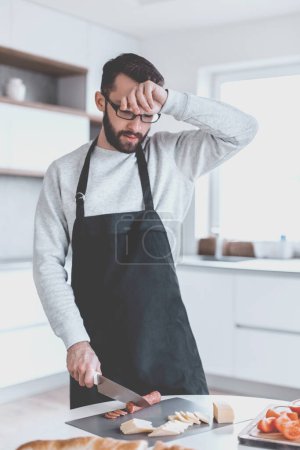 Photo for Tired man makes sandwiches in his kitchen - Royalty Free Image