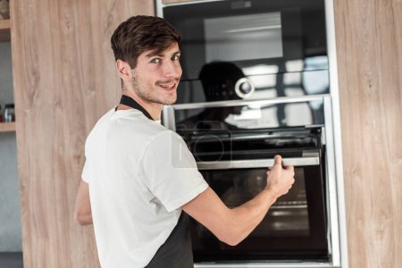 Photo for Man opening the oven in the home kitchen - Royalty Free Image