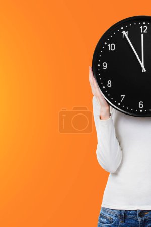 Photo for Woman holding a clock over face - Royalty Free Image