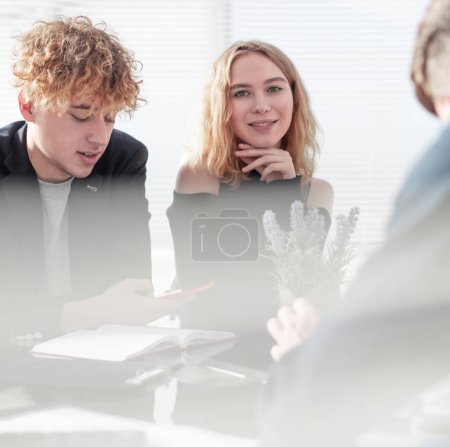 Photo for Full concentration at work. Group of young business people working and communicating while sitting at the office desk together with colleagues - Royalty Free Image